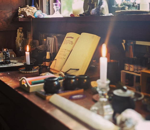 Vintage desk with candles, books, and other objects in a dimly lit room.